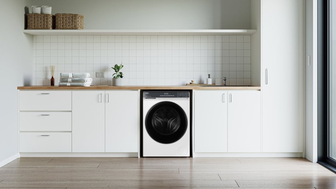 Haier 7.5kg front load washing machine in a modern white laundry room