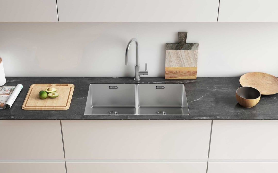 Double bowl sink in a modern kitchen with avocados on a cutting board