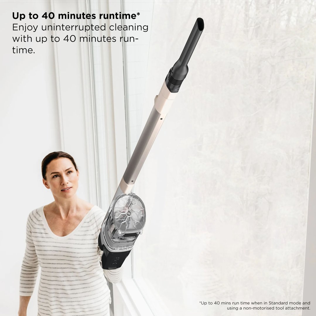 Woman using a Shark handstick vacuum to clean a high window