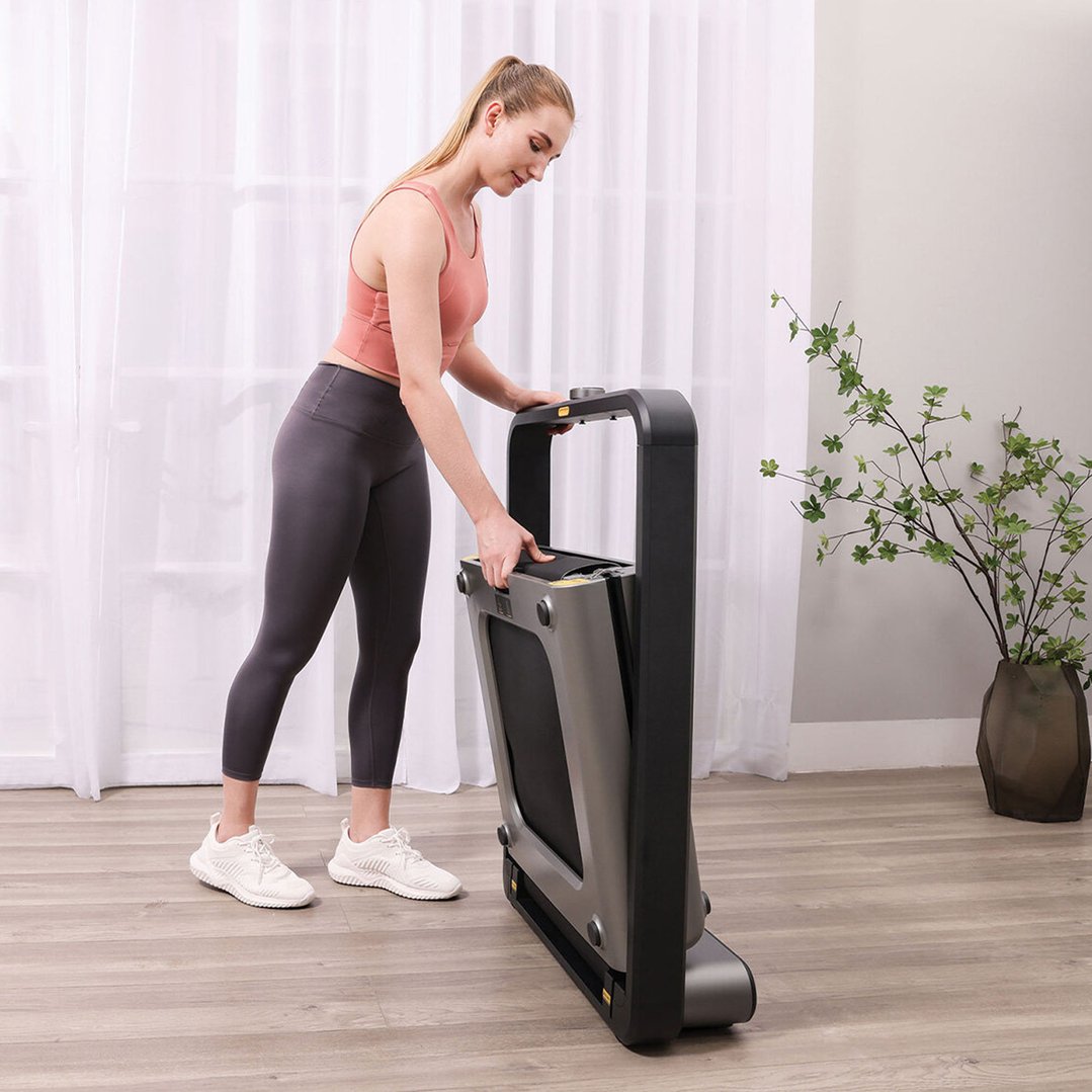 Woman folding a treadmill in a room with white curtains