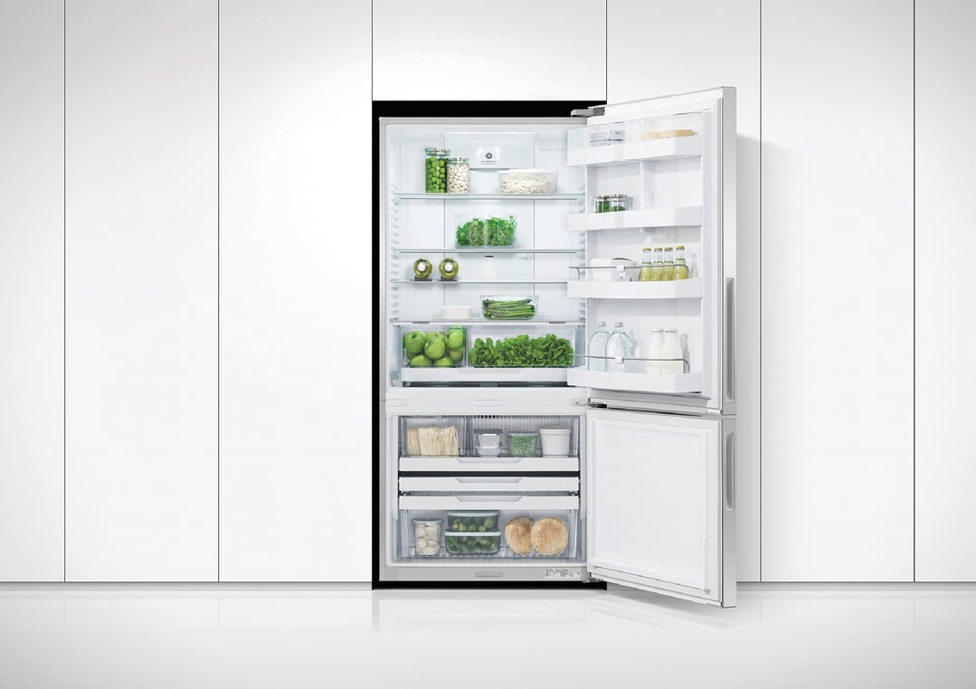Open refrigerator freezer filled with fresh produce in a modern kitchen setting