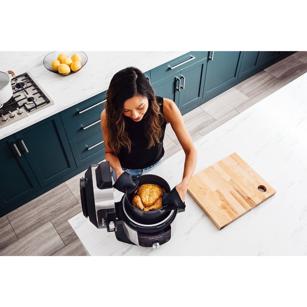 Woman placing a whole chicken into a Ninja Foodi Smart Lid Multicooker