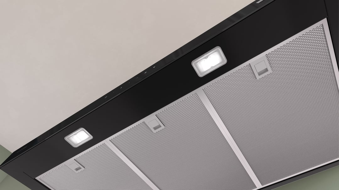 Close-up of a black Bosch rangehood with lights on, viewed from below