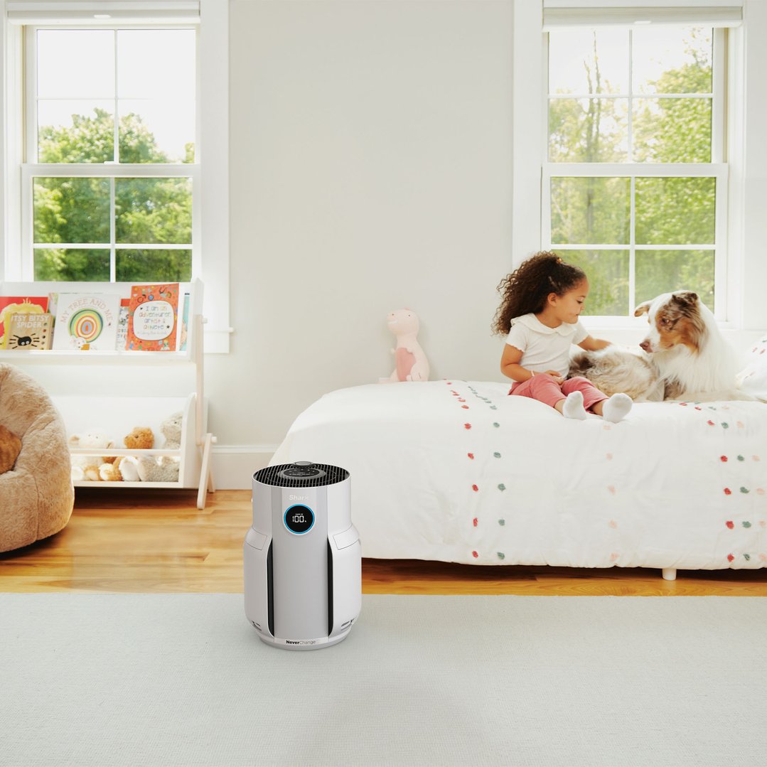 SHARK air purifier on the floor in a child's bedroom with a girl and dog
