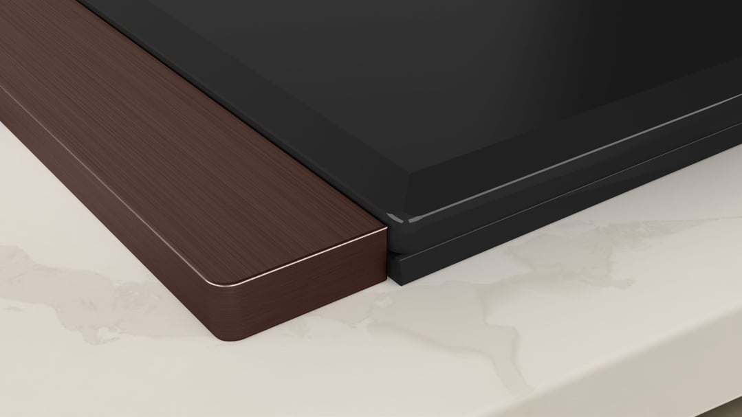 Close up of a cooktop with a metallic silver trim on a light countertop