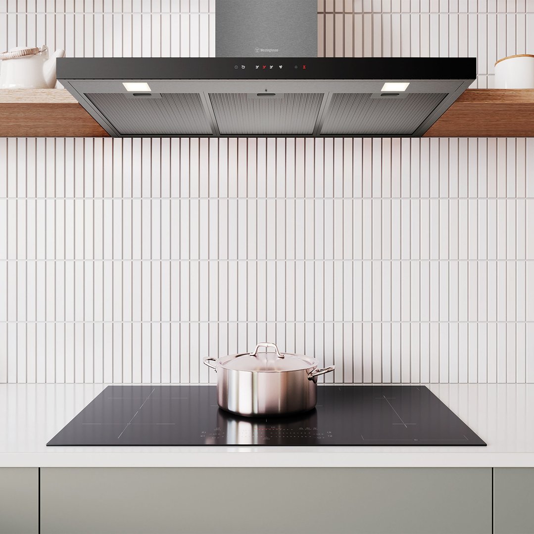 Dark stainless steel canopy rangehood installed above an induction cooktop with a pot