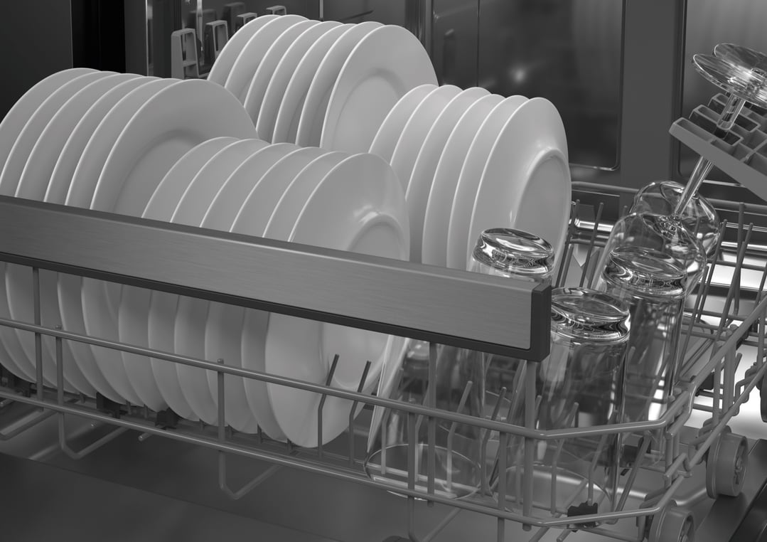 Close up of a dishwasher rack filled with clean white plates and glasses