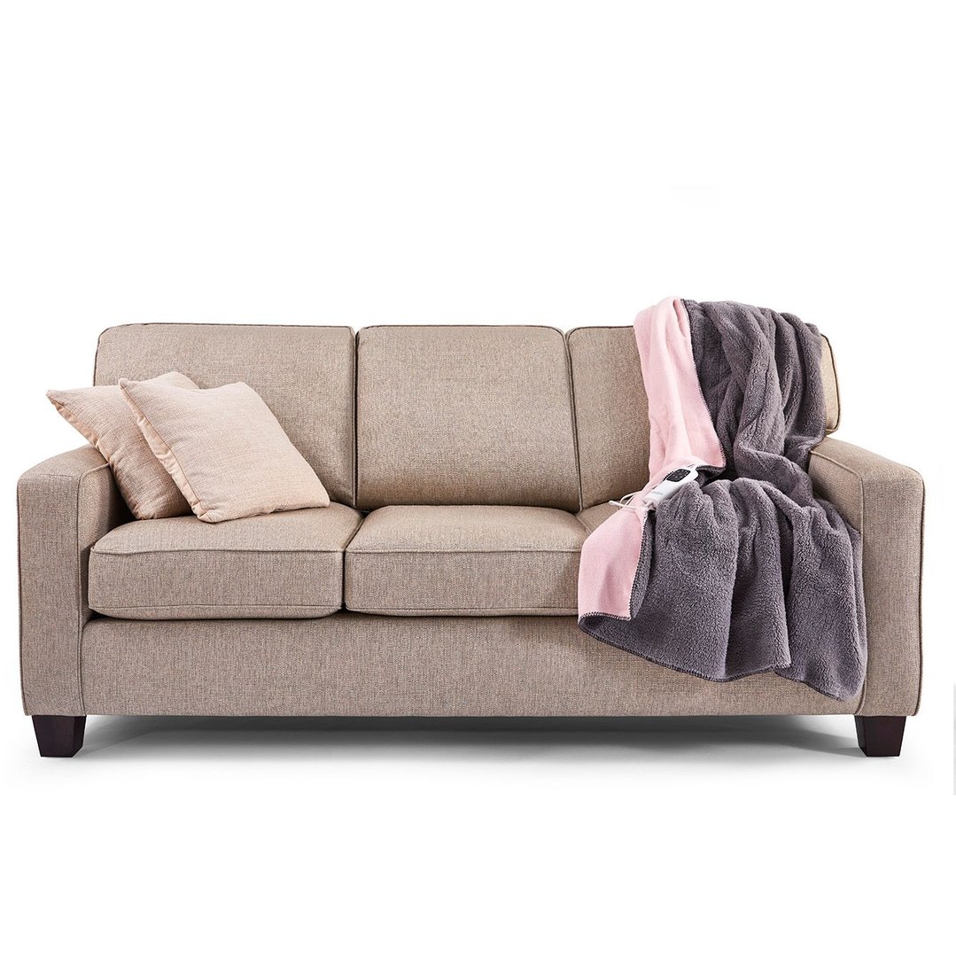 Sunbeam electric blanket draped over a sofa with two pillows