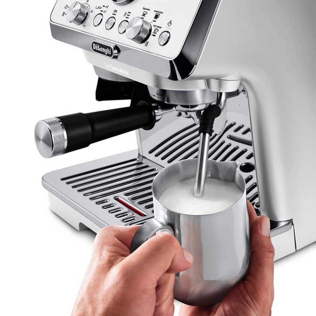 Hand frothing milk with the steam wand of a white coffee machine