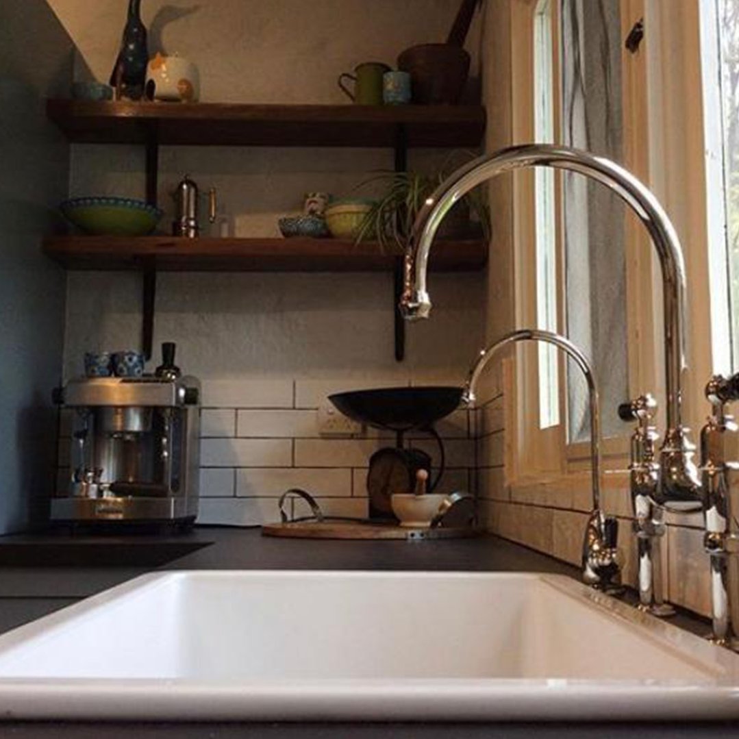 White fireclay sink in a kitchen with shelves and a coffee machine