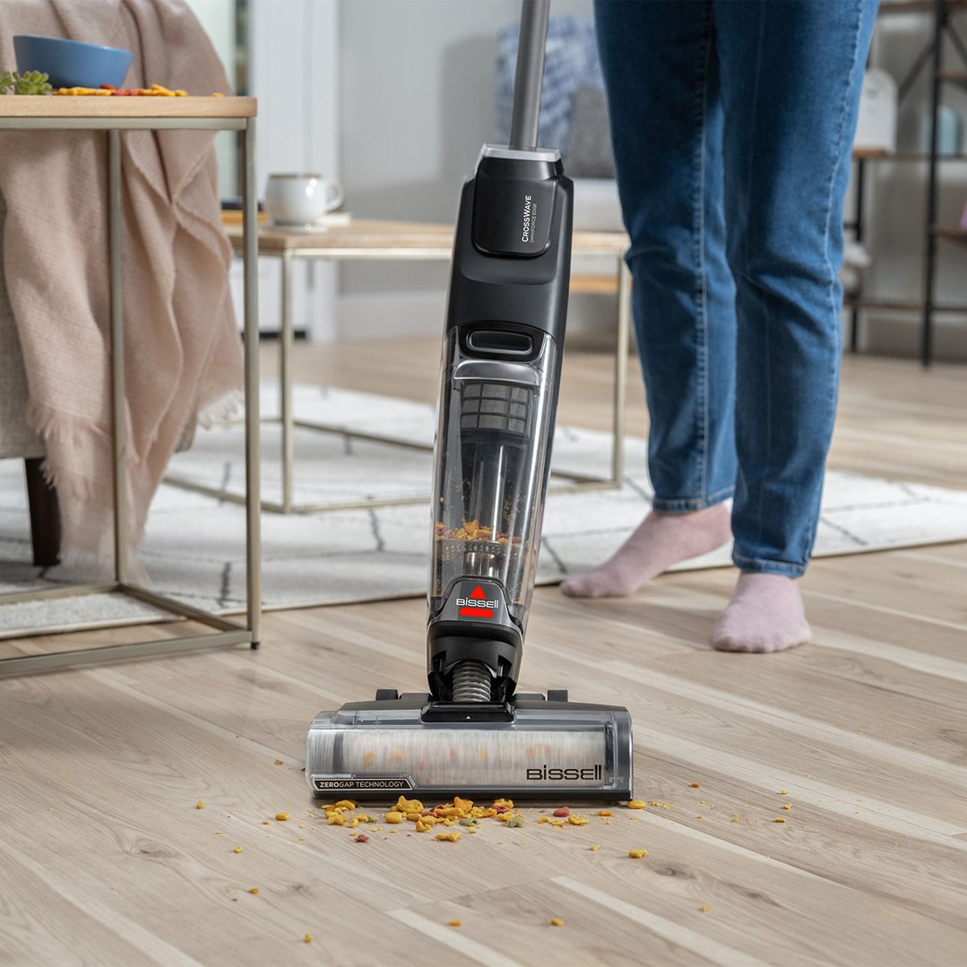 A Bissell vacuum cleaner cleaning up spilled cereal on a wooden floor
