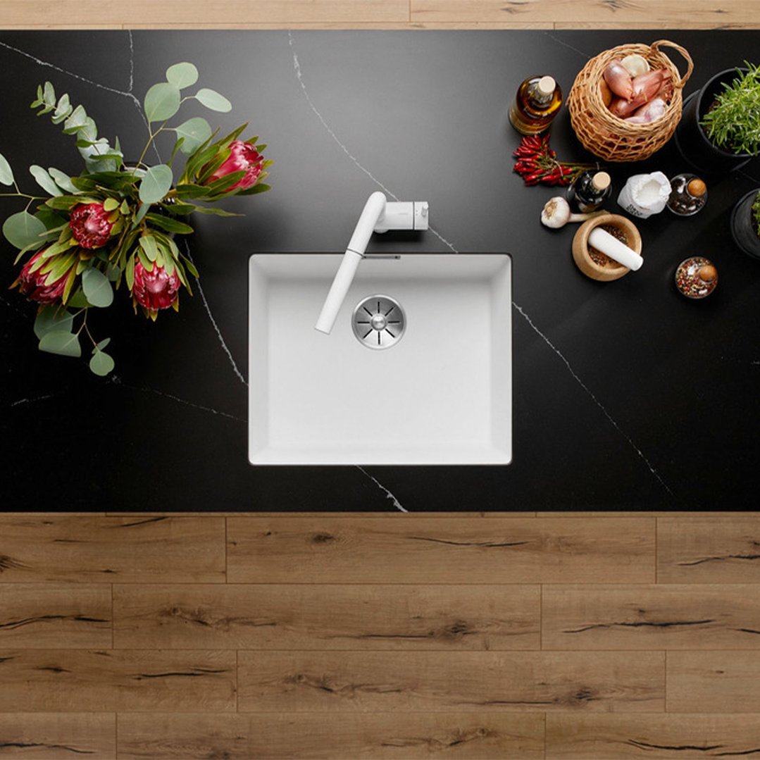 Overhead view of a white single bowl undermount sink with a white tap