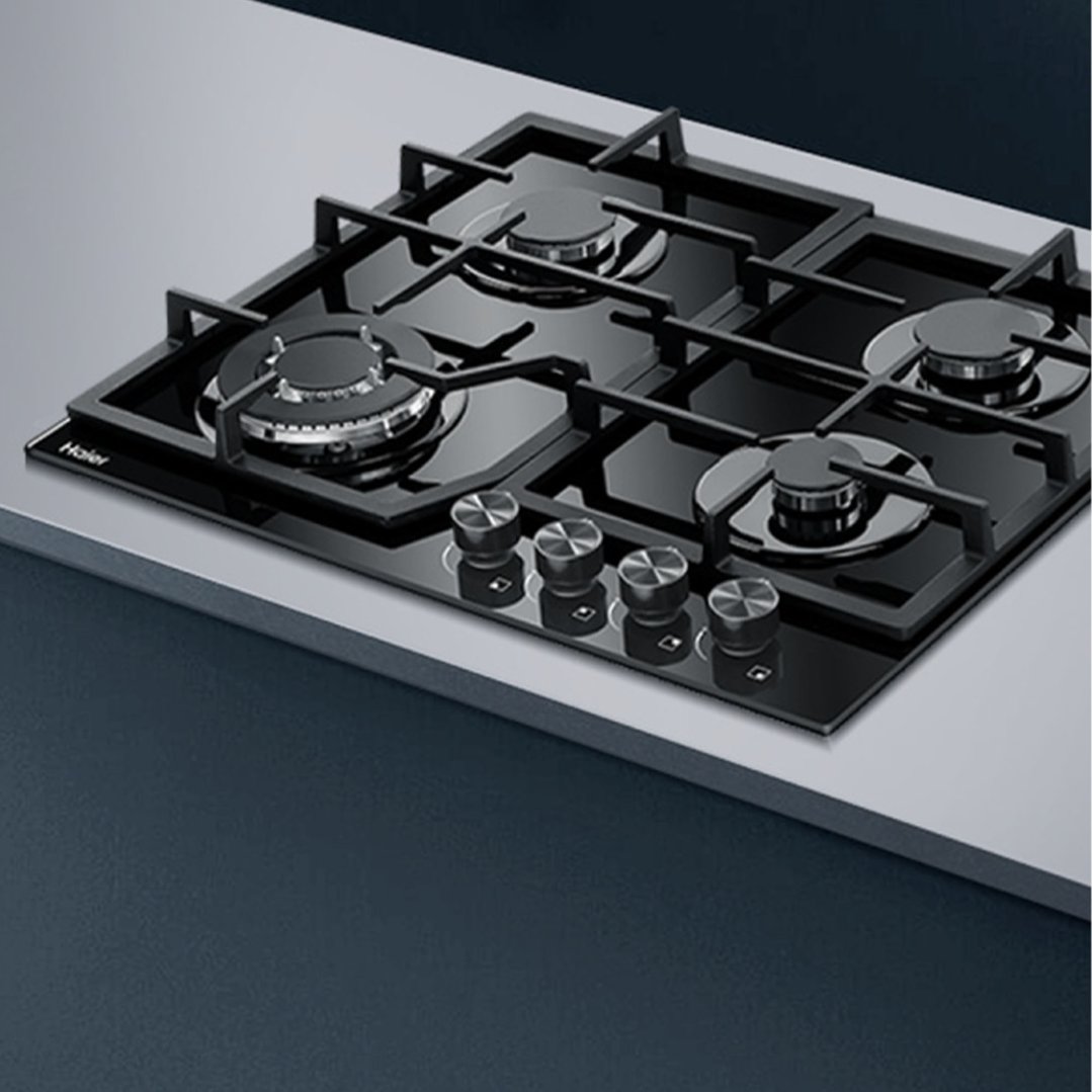 Black gas on glass cooktop with four burners and control knobs on a countertop