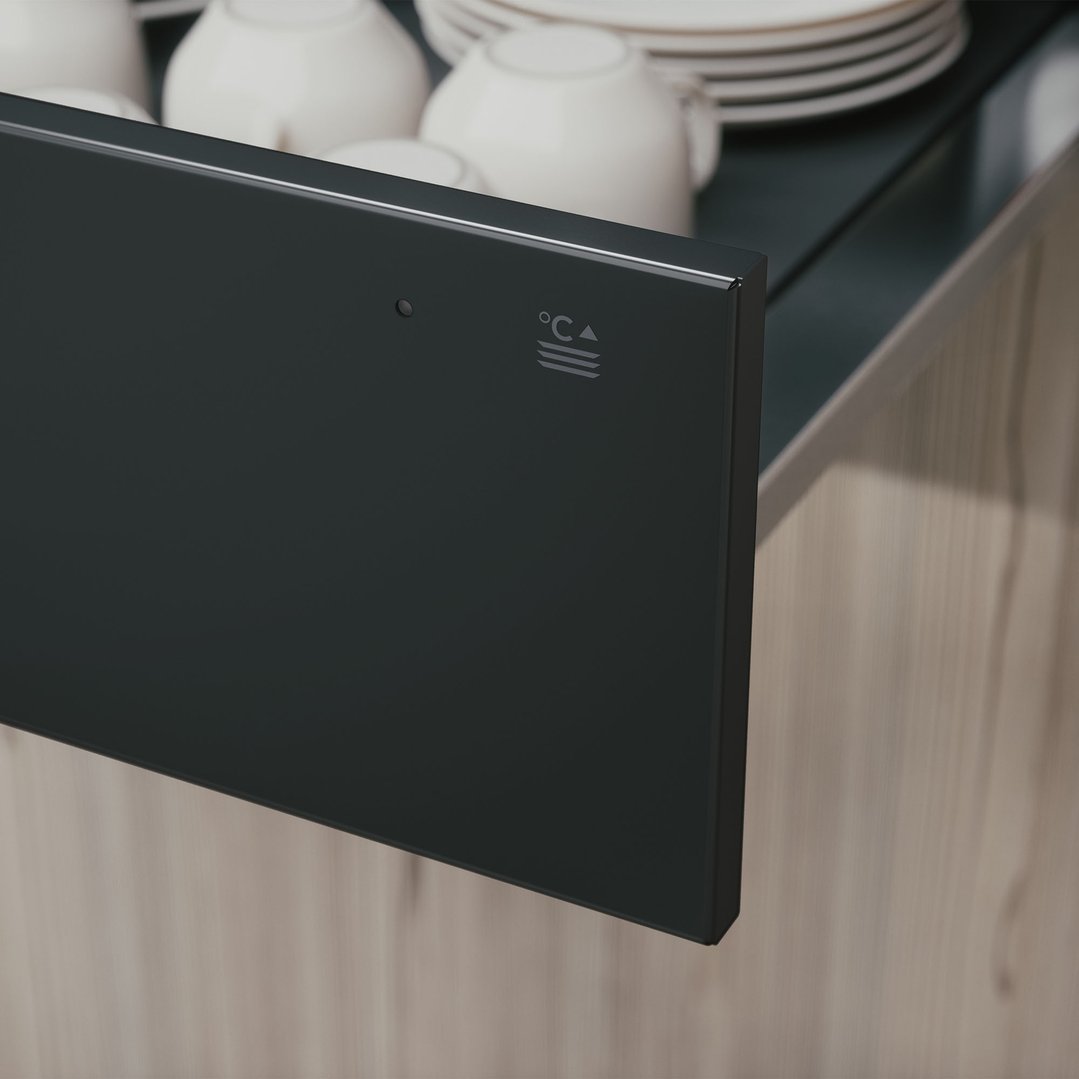 Graphite black warming drawer partially open with cups and plates inside