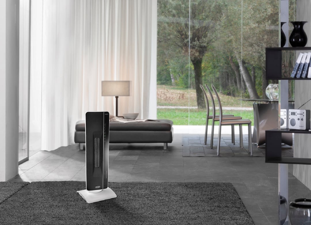 Black tower ceramic heater on a white stand in a modern living room