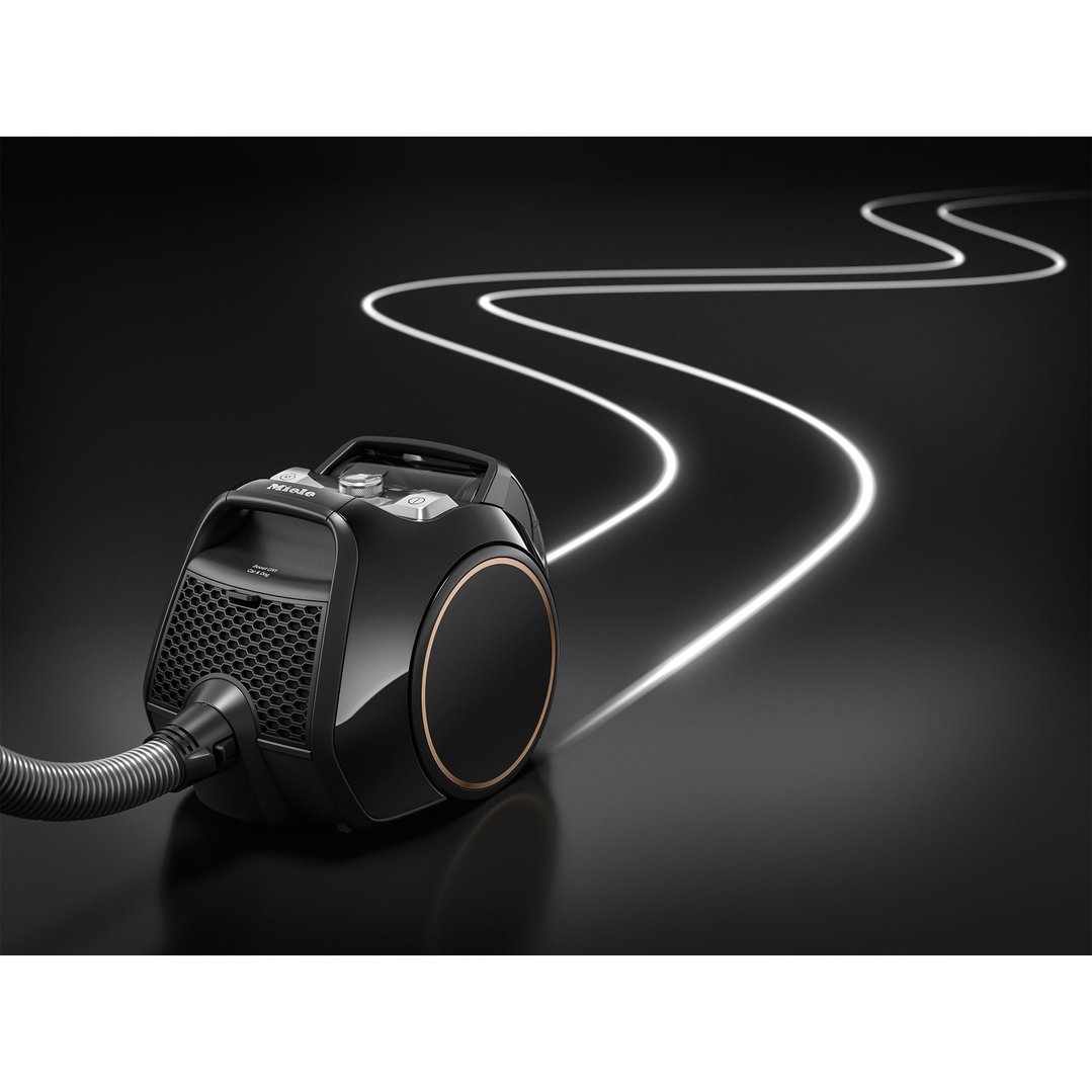 Black Miele Boost CX1 vacuum cleaner on a dark surface with light trails