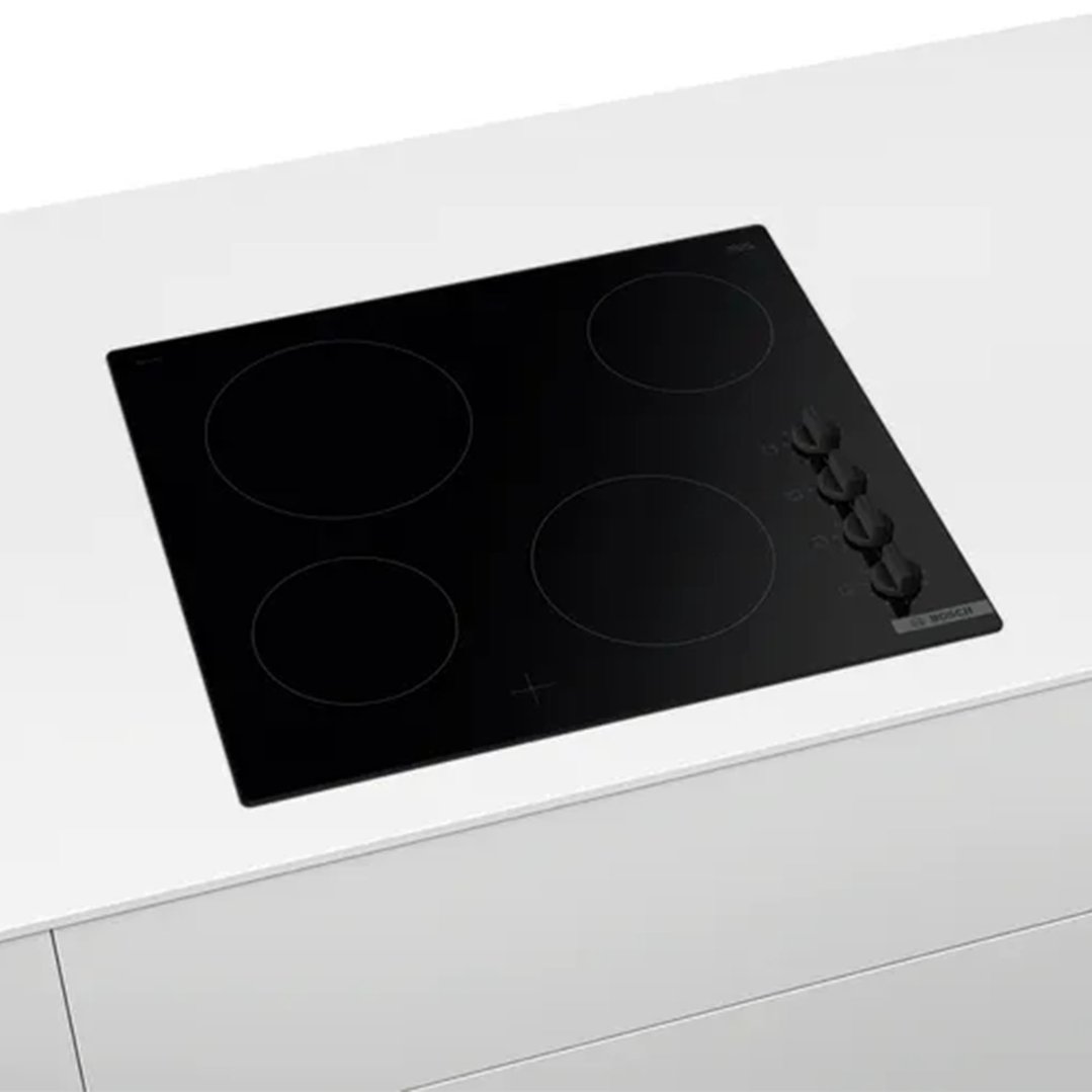 Black electric cooktop with four burners and control knobs built into a white countertop