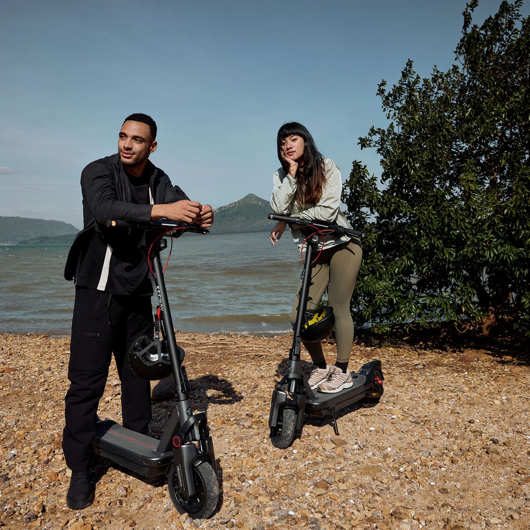 Two people with Ninebot MAX G3 electric kickscooters on a rocky beach