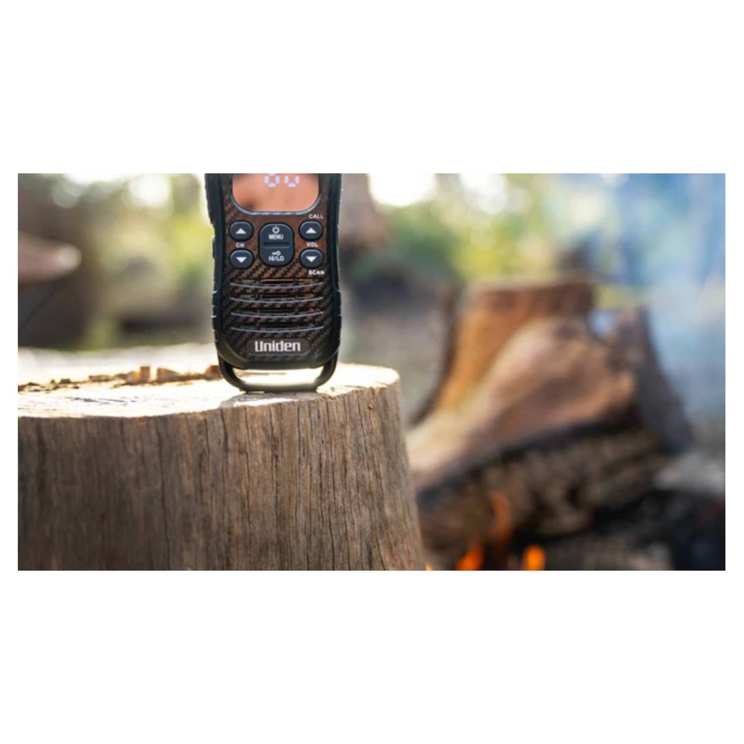 Uniden UHF radio on a tree stump with a campfire in the background