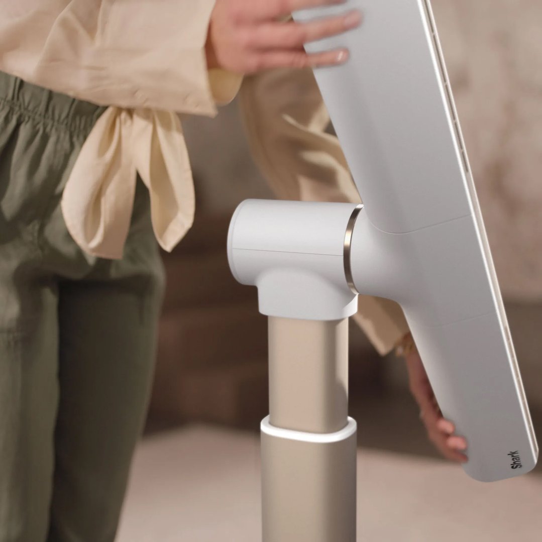 Person adjusting a white Shark fan in a home setting