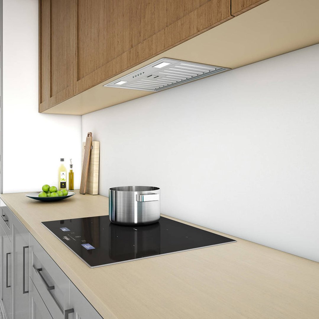Undermount rangehood installed above an induction cooktop with a pot in a modern kitchen