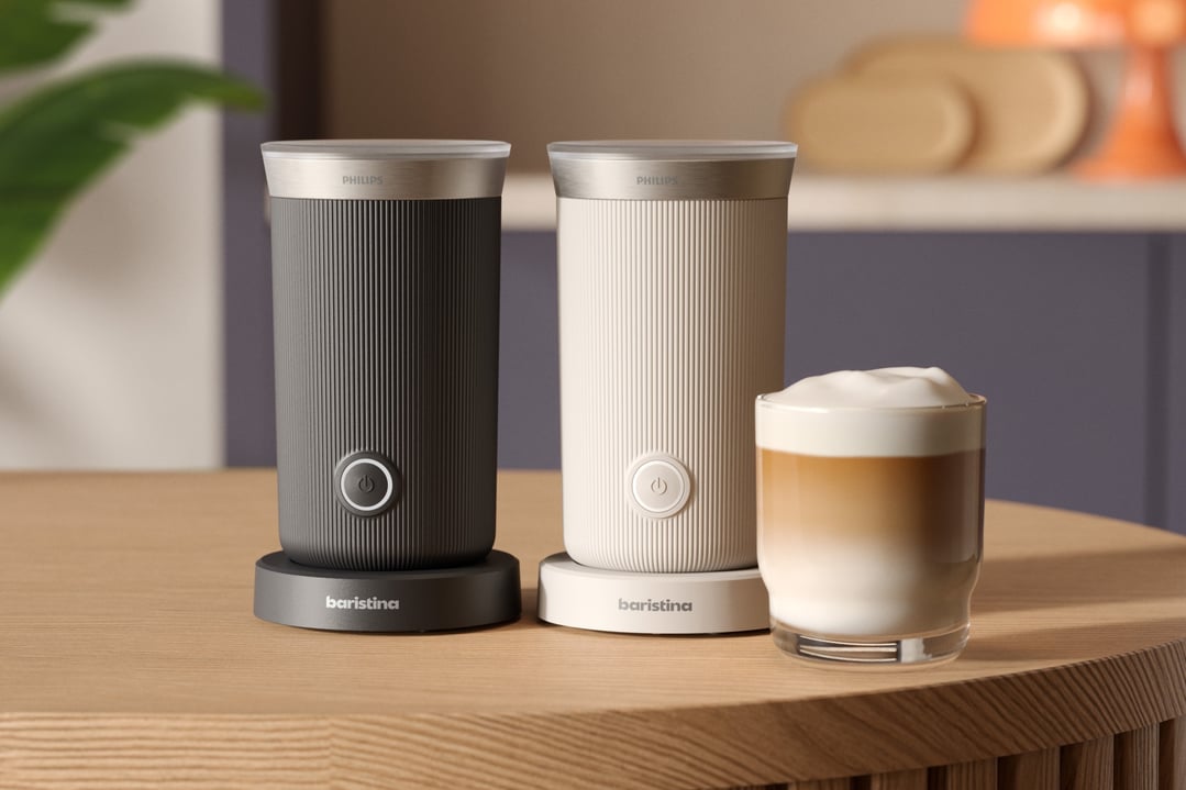 Two Philips Baristina Milk Frothers on a wooden table with a glass of latte