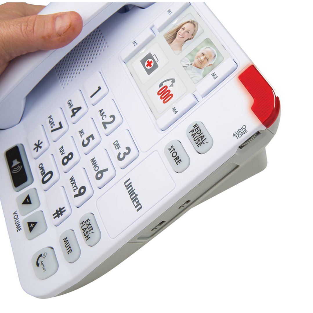 Hand holding a white corded phone system with large buttons and memory keys