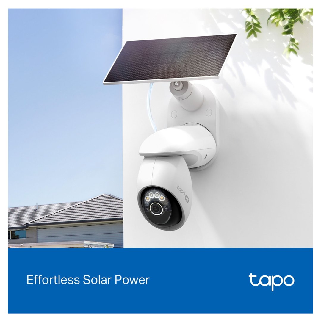 Solar-powered security camera mounted on a white wall with a house in the background