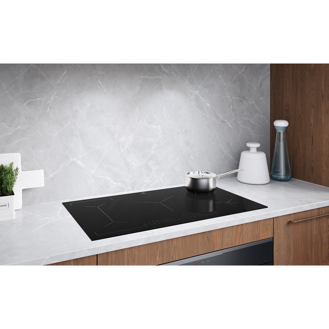 Electrolux induction cooktop with a pot on a kitchen counter with marble backsplash