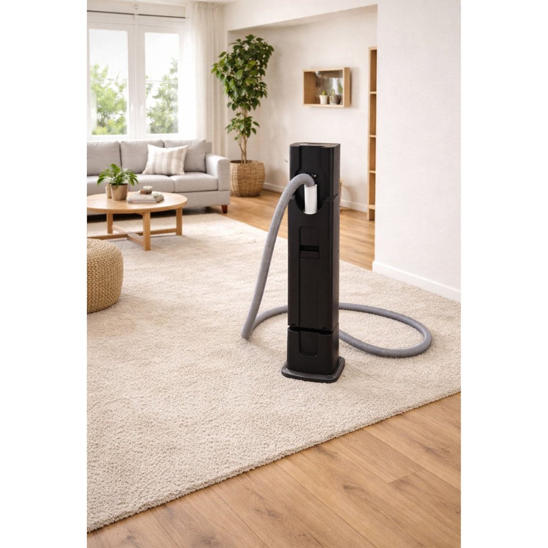 Black station vacuum cleaner with hose in a living room with a light rug