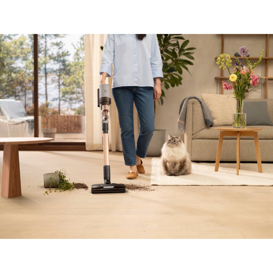 Woman vacuuming spilled plant soil from the floor with a handstick vacuum