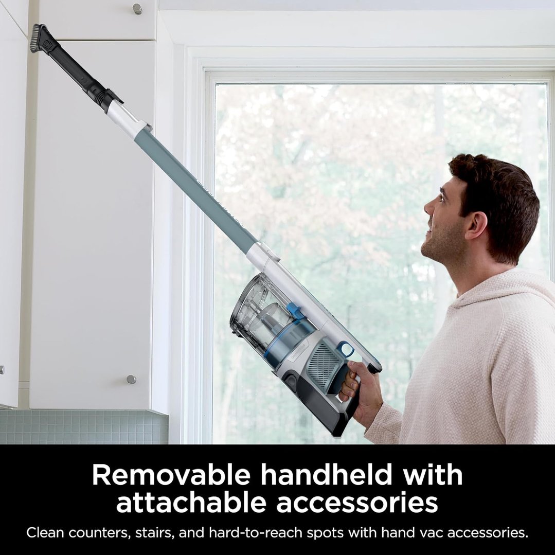 Man using a Shark cordless stick vacuum to clean a high cabinet