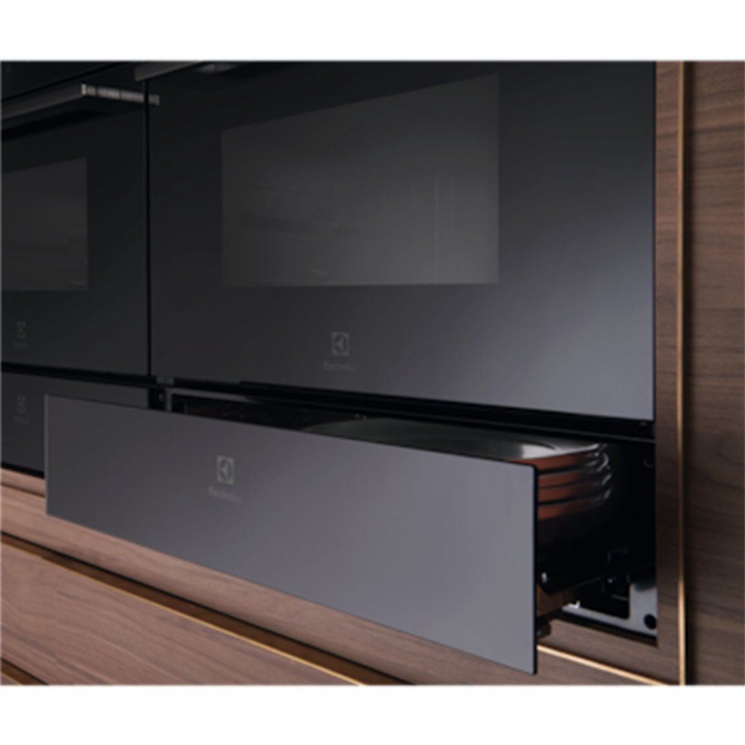 Built-in warming drawer partially open, showing a pot inside, in a kitchen setting