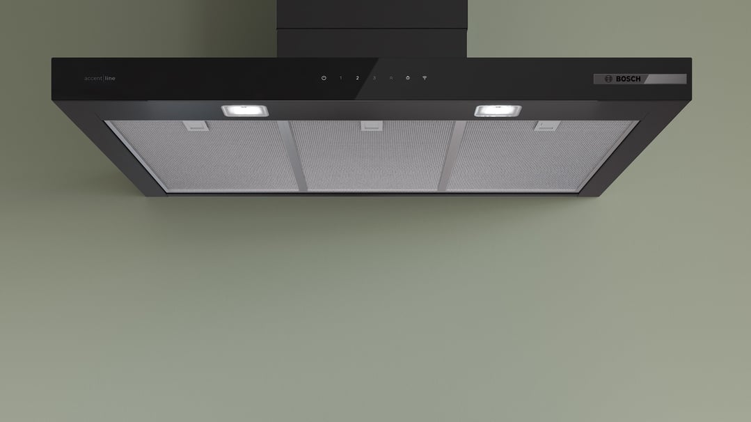 Black Bosch accent line rangehood with controls and lights, mounted on a green wall