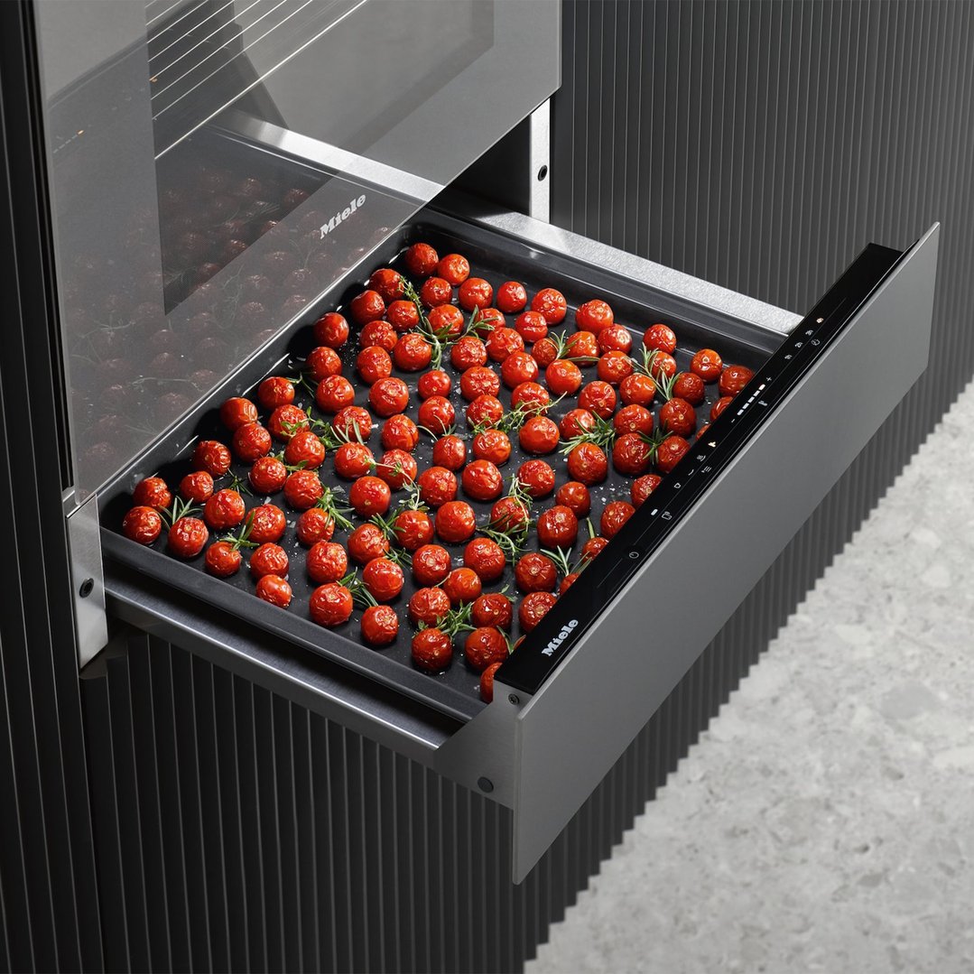 Gourmet warming drawer pulled out with roasted tomatoes and herbs inside