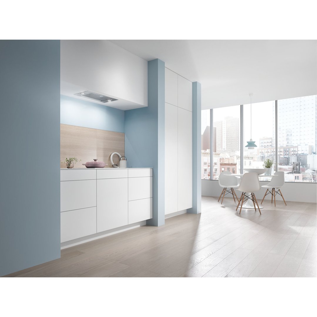 Built-in rangehood in a modern kitchen with light blue walls and white cabinetry
