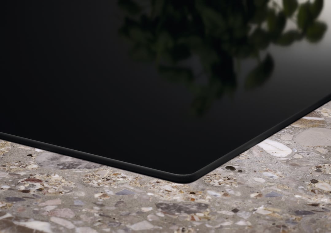 Close up of an induction cooktop on a speckled countertop with reflections
