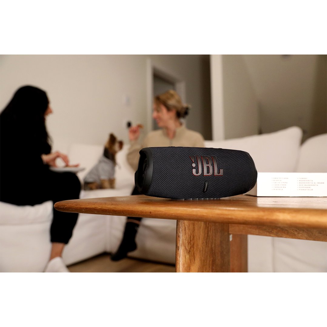 Black JBL portable speaker on a wooden table in a living room