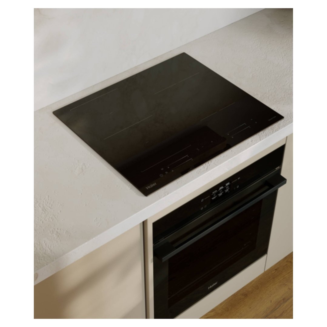 Black induction cooktop and oven built into a light-colored kitchen counter and cabinet