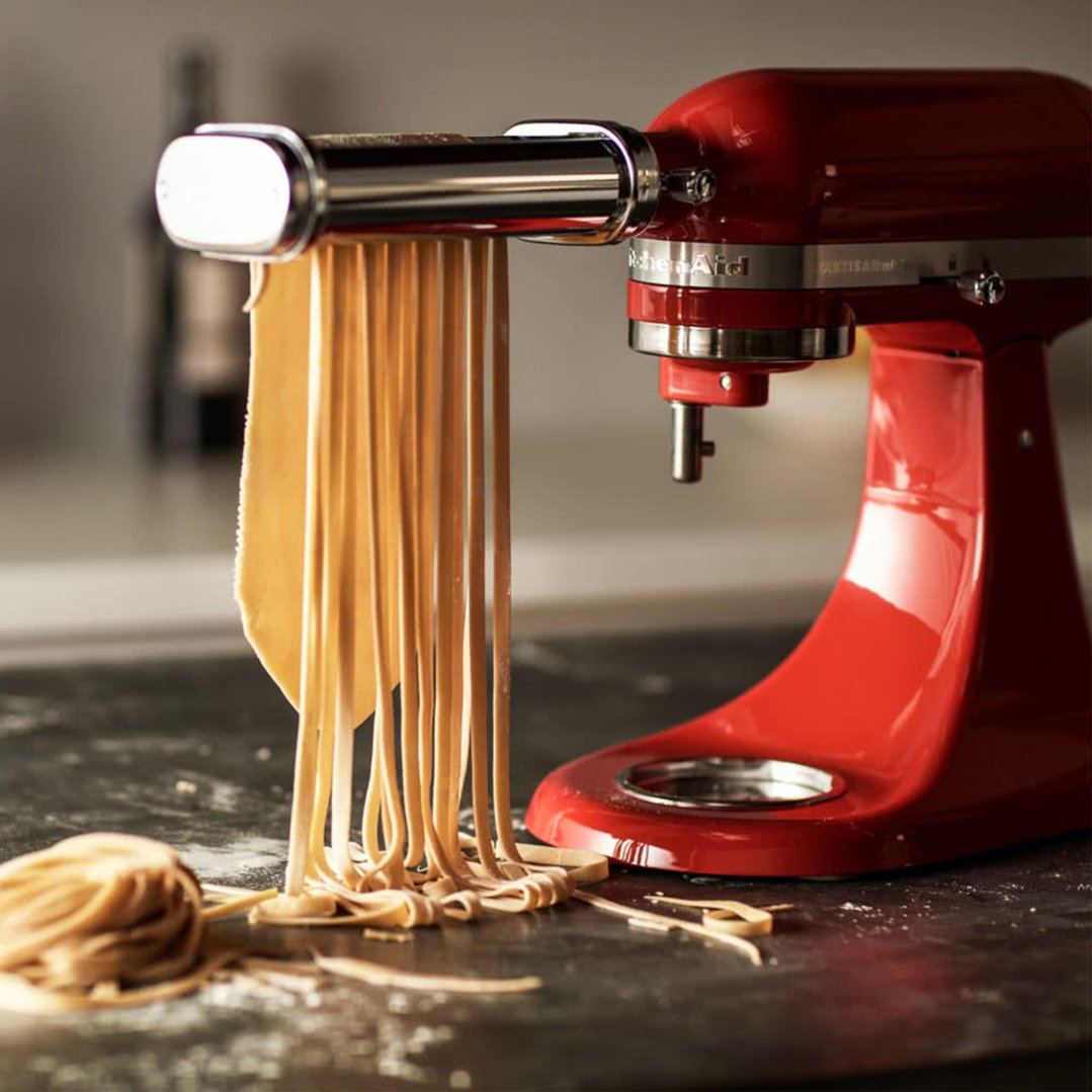 Pasta roller set attached to a red stand mixer making fresh pasta