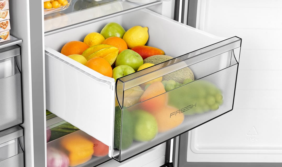 Open fridge drawer filled with various fruits and vegetables