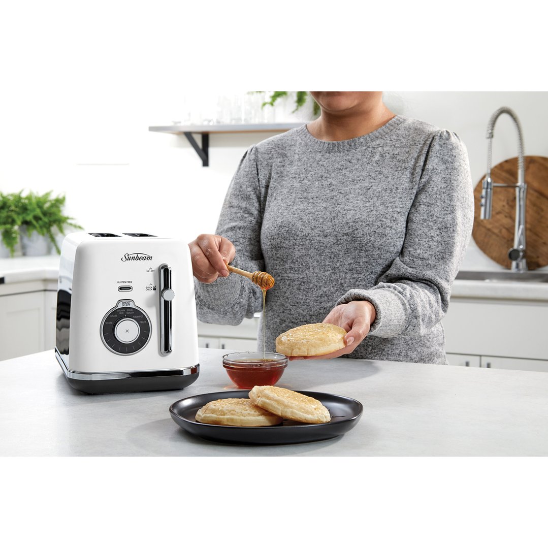Woman drizzling honey on toasted bread next to a white Sunbeam toaster