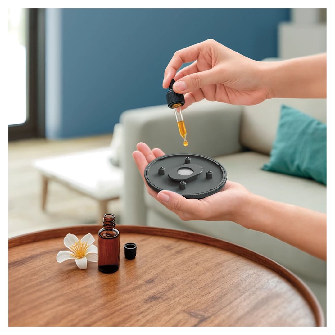 Hands adding essential oil drops to the top of a Philips pedestal fan