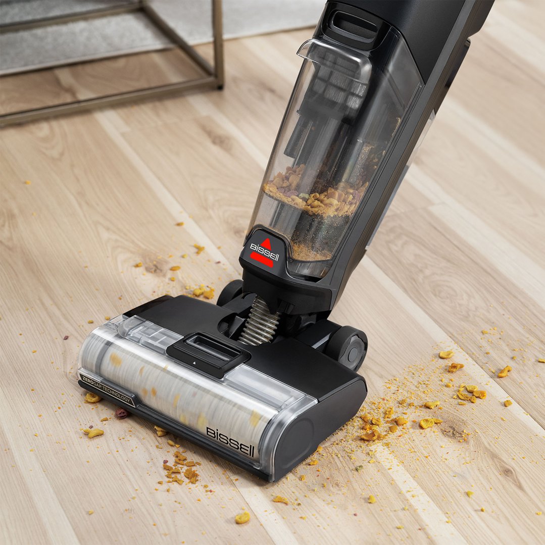 BISSELL CrossWave OmniForce vacuum cleaner picking up debris from a wooden floor