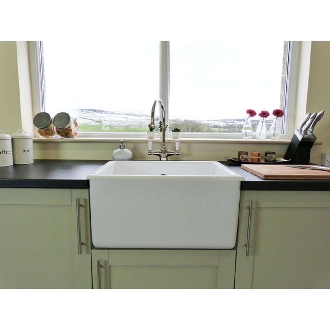 White ceramic sink in a kitchen with a window overlooking a snowy landscape