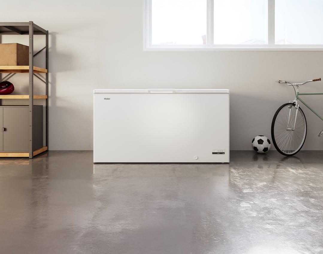 White Haier chest freezer in a garage with a bicycle and soccer ball