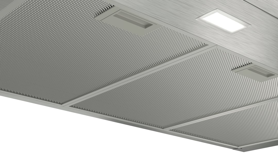 Close up of a rangehood with mesh filters and an illuminated light