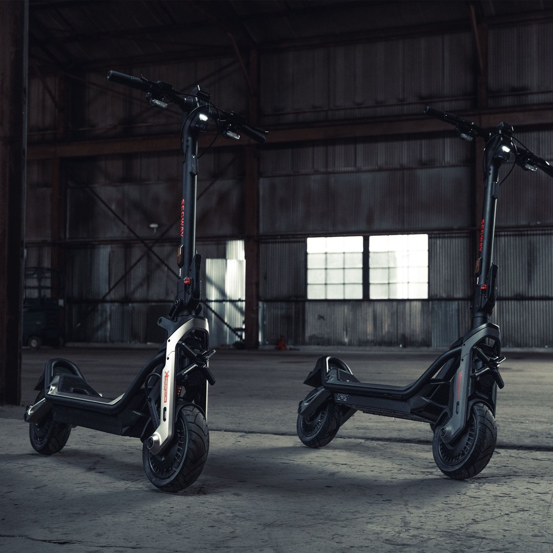 Two Segway electric super scooters parked in a large, dark warehouse