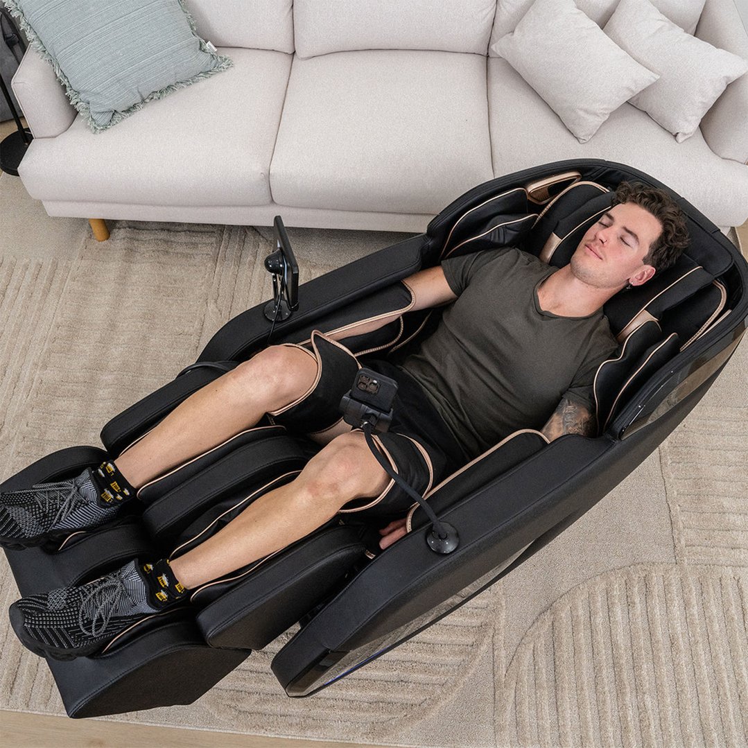 Man sleeping in a black massage chair in a living room setting