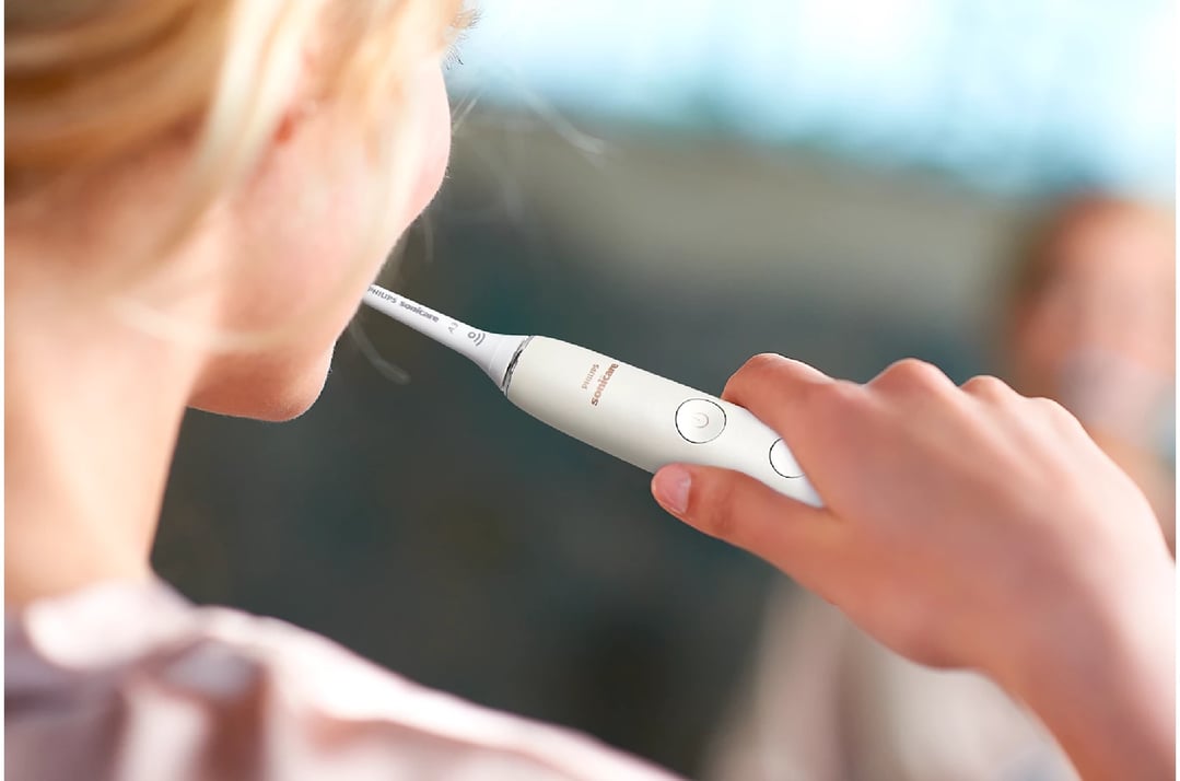 Person brushing teeth with a white Philips Sonicare electric toothbrush